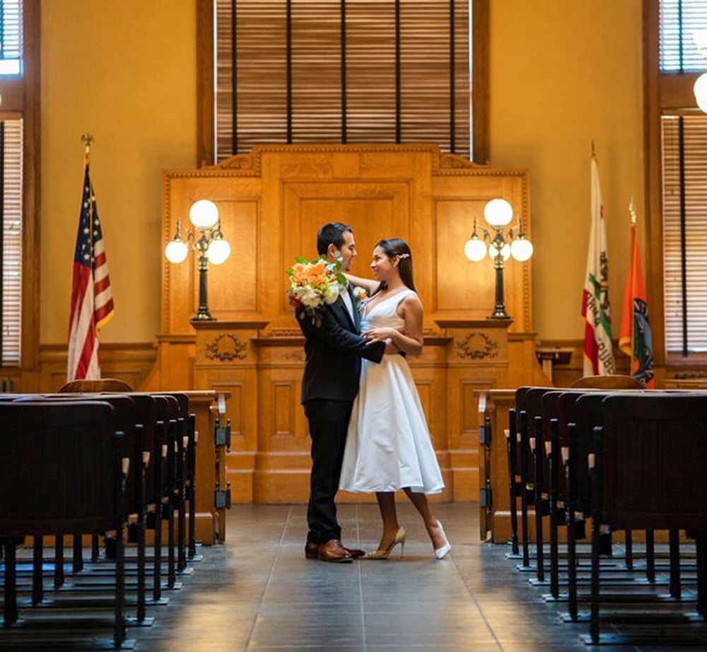 A bride and groom are kissing in the historic courtroom in Santa Ana