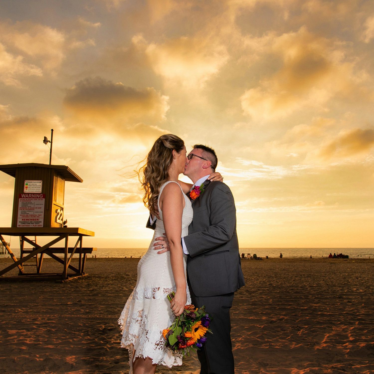 A bride and groom kissing on the beach at sunset in Newport Beach. 