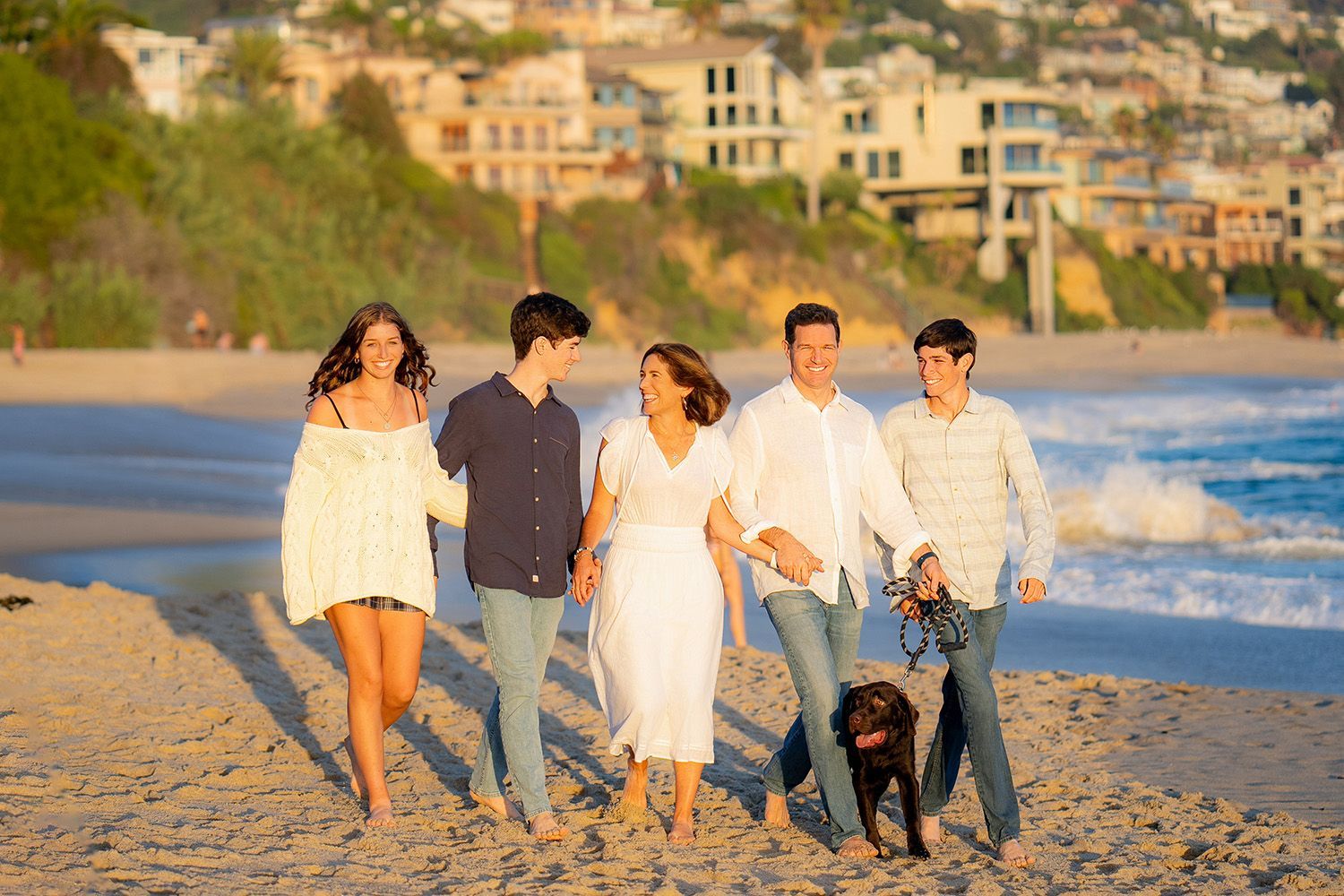 Dana Point Family Photography A family is walking their dog on the beach.