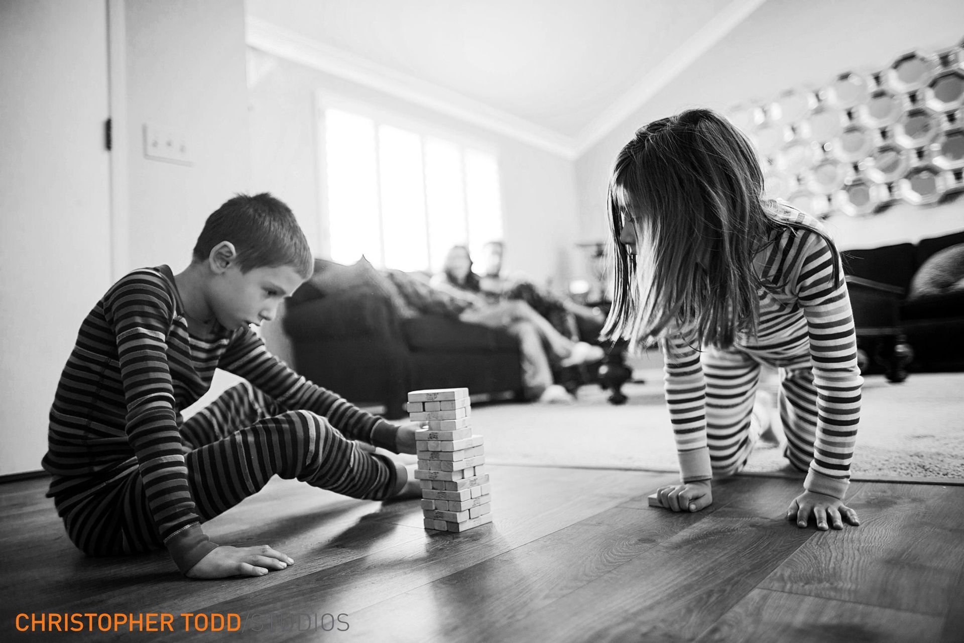 A boy and a girl are playing with blocks on the floor.