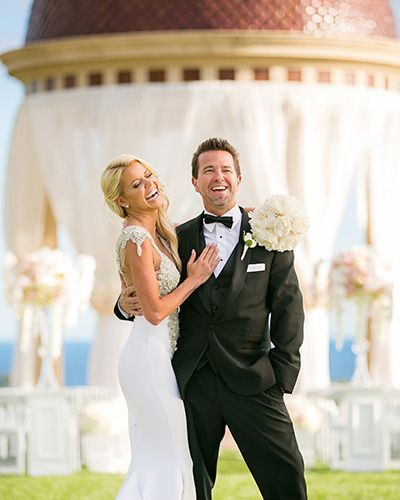 A bride and groom are posing for a picture in front of a dome.