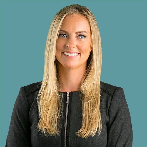 A woman with long blonde hair is wearing a black jacket and smiling.