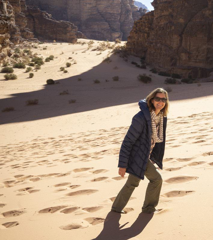 Ilana Griffiths in a blue jacket is standing in the sand