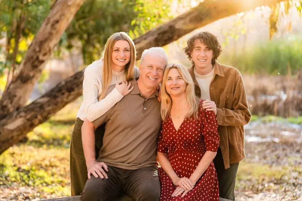 Huntington Beach Photographer A family is posing for a picture under a tree in central park, Huntington beach.