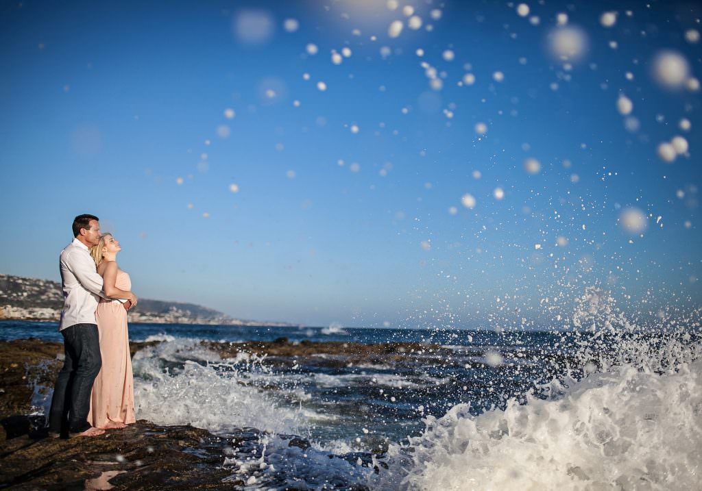 An engaged couple is posing for a picture on the beach in Orange County, ca.
