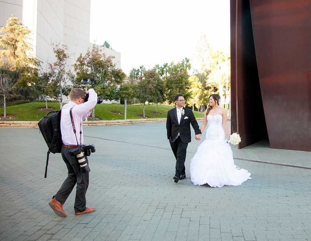 Christopher Todd and Orange County Photographer in a blue shirt is holding a camera and smiling.