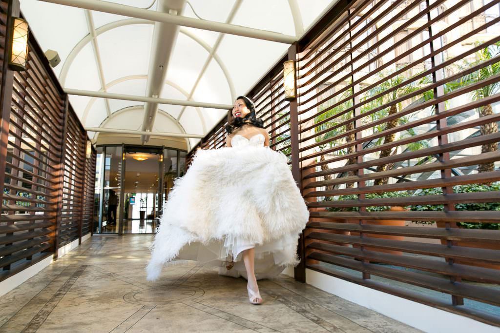 A bride in a wedding dress is running down a hallway at the Maybourne in Beverly Hills