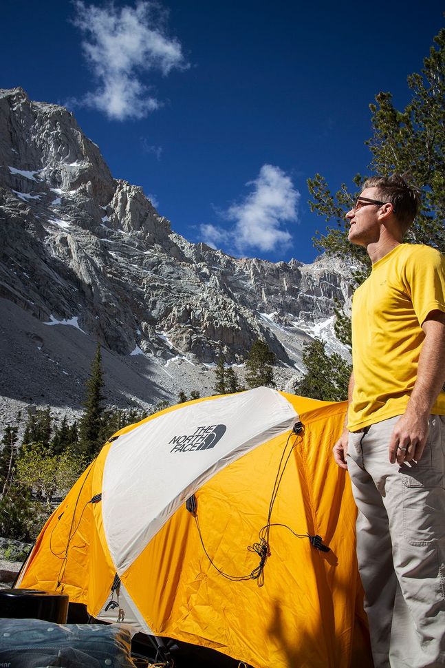 Christopher Todd in a yellow shirt is standing in front of a yellow tent at Mount Whitney.