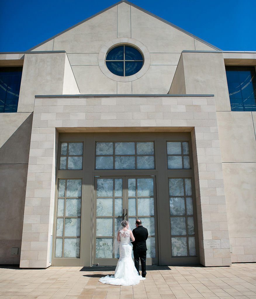 A bride and her father stand in front of a large our lady queen of angels in Newport Beach waiting for their entrance