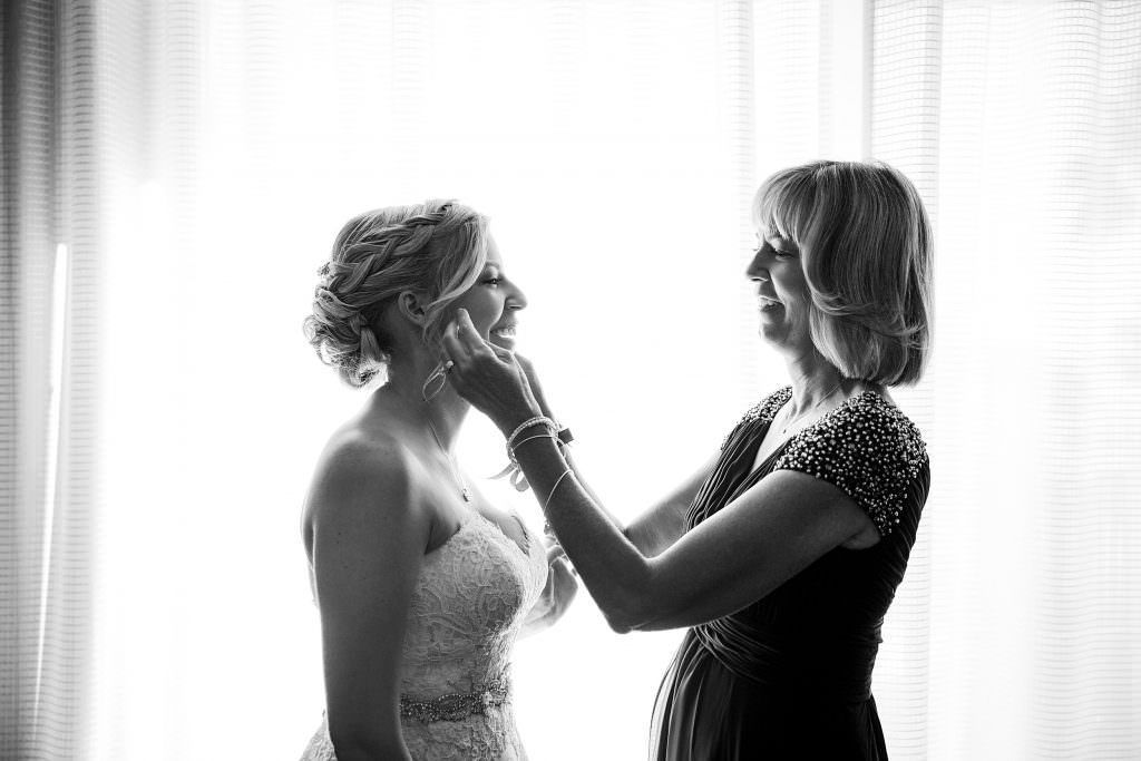 A black and white photo of a bride and her mother getting ready for her wedding.
