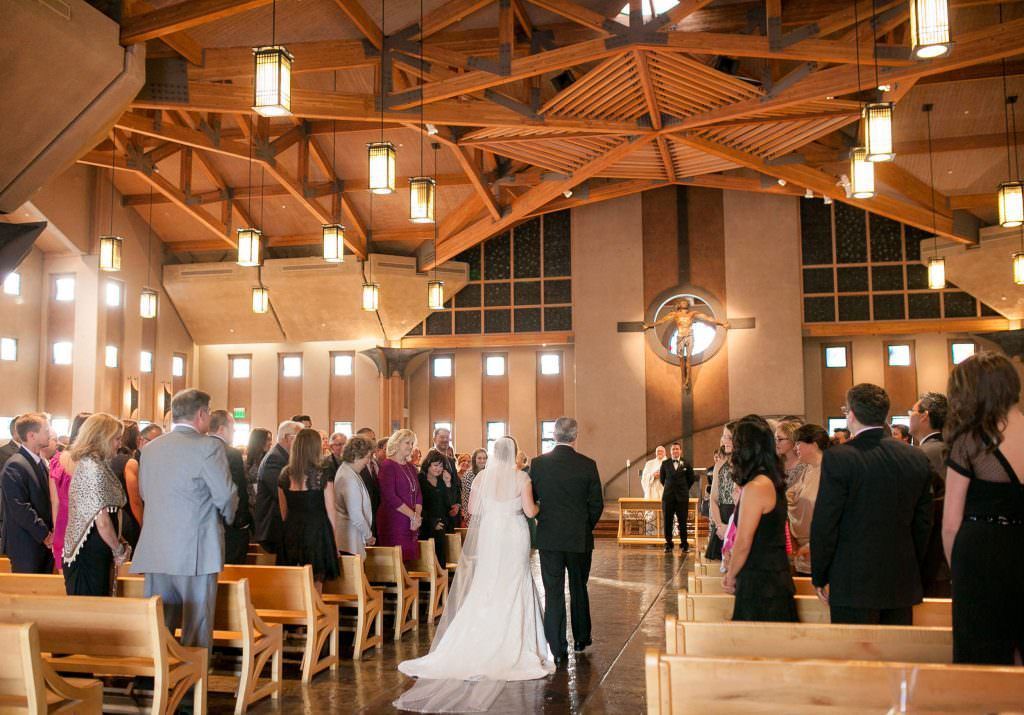A bride and groom are walking down the aisle of a church.