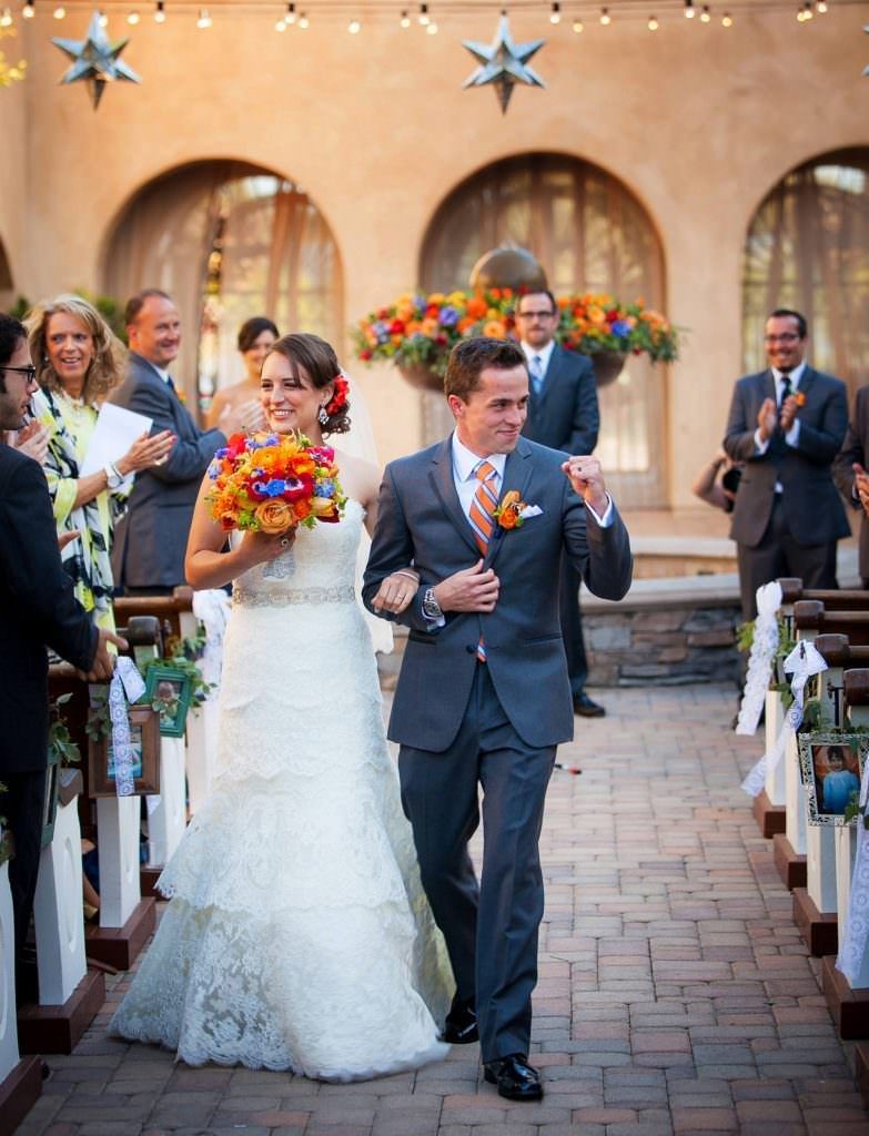 A bride and groom are walking down the aisle at their wedding