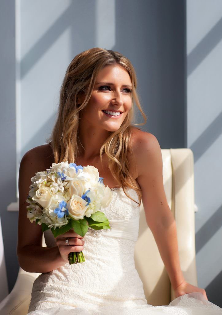 A bride in a white dress is sitting in a chair holding a bouquet of flowers.