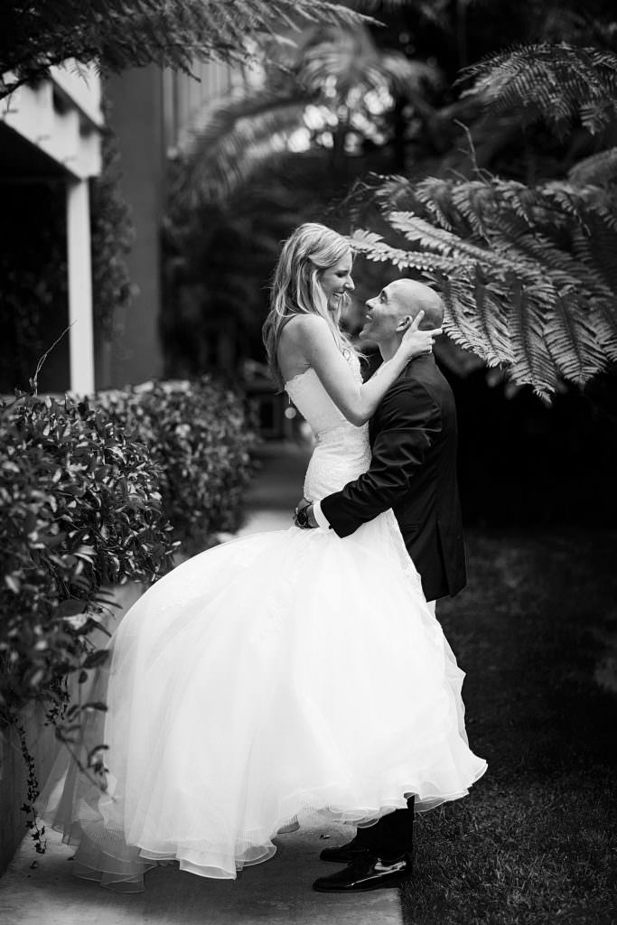 A bride and groom are kissing in a black and white photo.