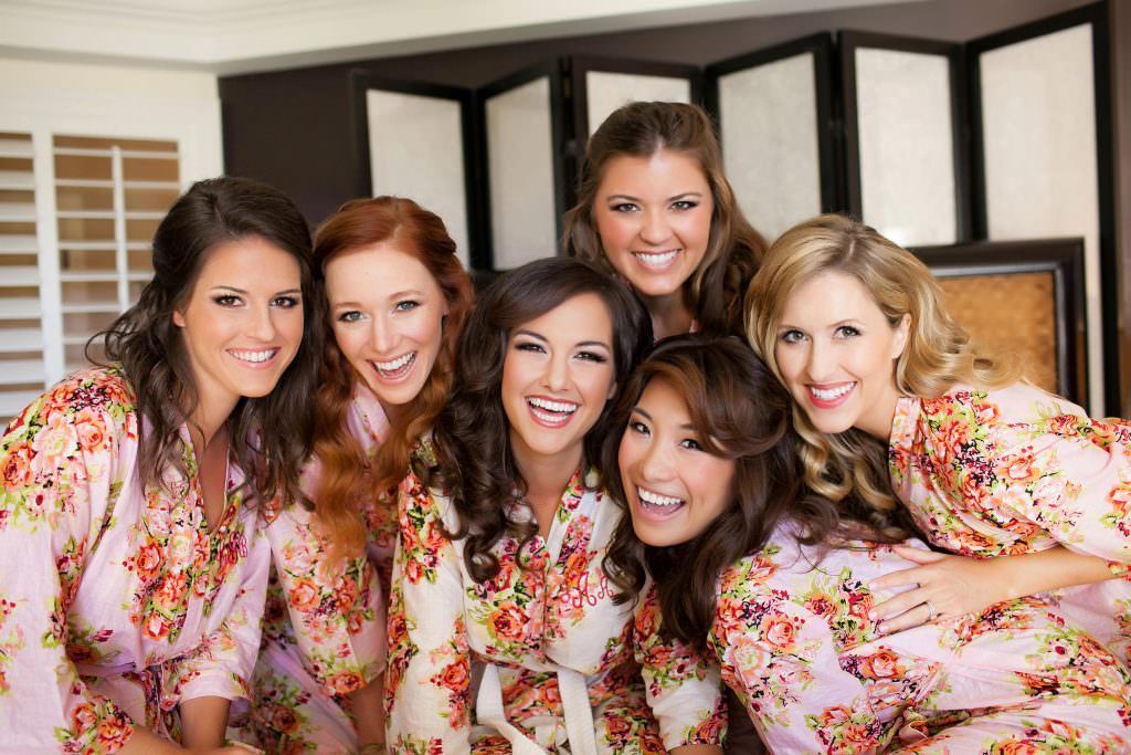 A group of bridesmaids wearing floral robes are posing for a picture at the Ritz Carlton