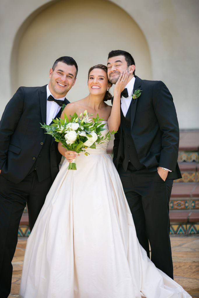 A bride and groom are posing for a picture with their groomsmen.