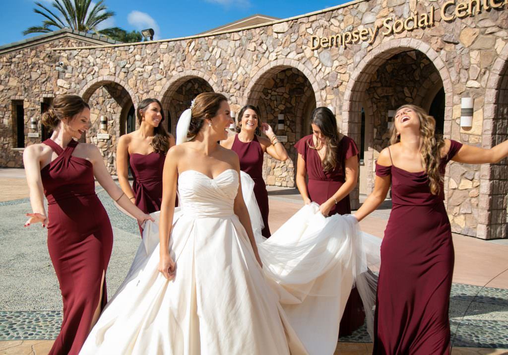 A bride and her bridesmaids are posing for a picture at a Catholic Church in Huntington Beach