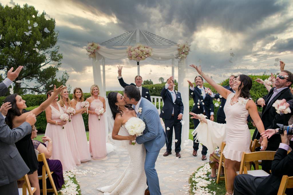 A bride and groom are kissing in front of their wedding party at La Venta Inn in Los Angeles.