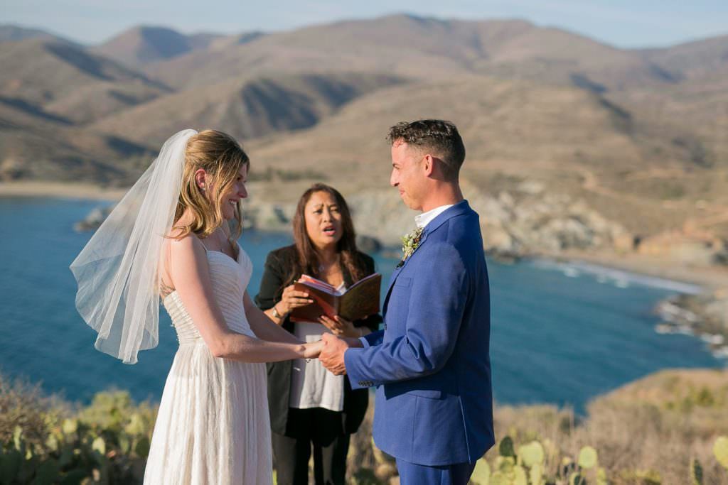 A bride and groom are getting married on top of a hill overlooking the ocean on Catalina Island.