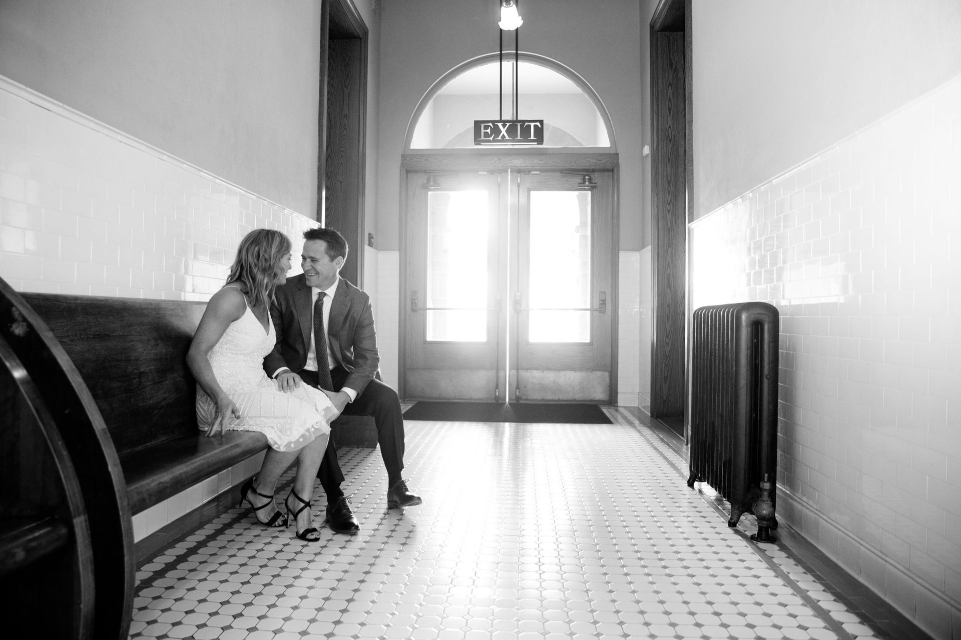 A bride and groom are sitting on a bench in the old courthouse