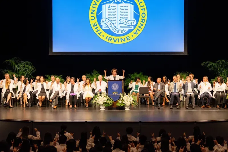 A group of people are standing on a stage in front of a large screen at conference