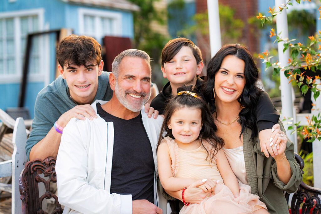A family is posing for a picture together on a porch.