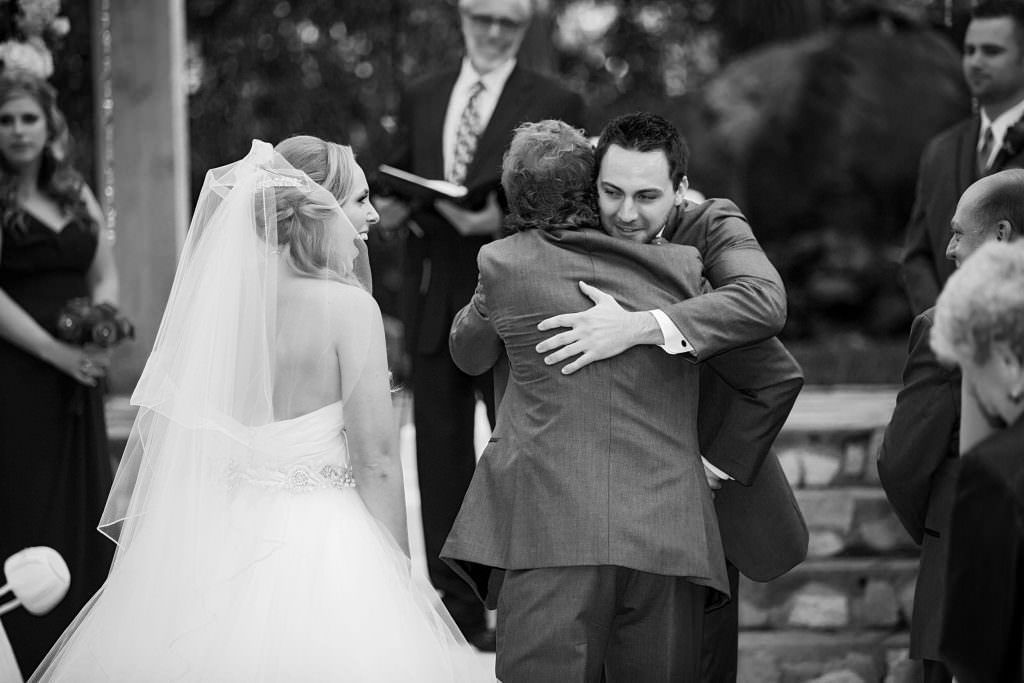 A bride and groom are hugging each other at their wedding ceremony.