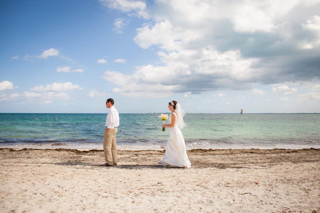 A bride and groom's first look on a beach before their wedding