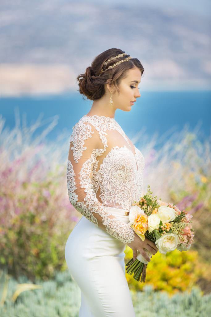 The Terranea bride is wearing a white lace dress and holding a bouquet of flowers.