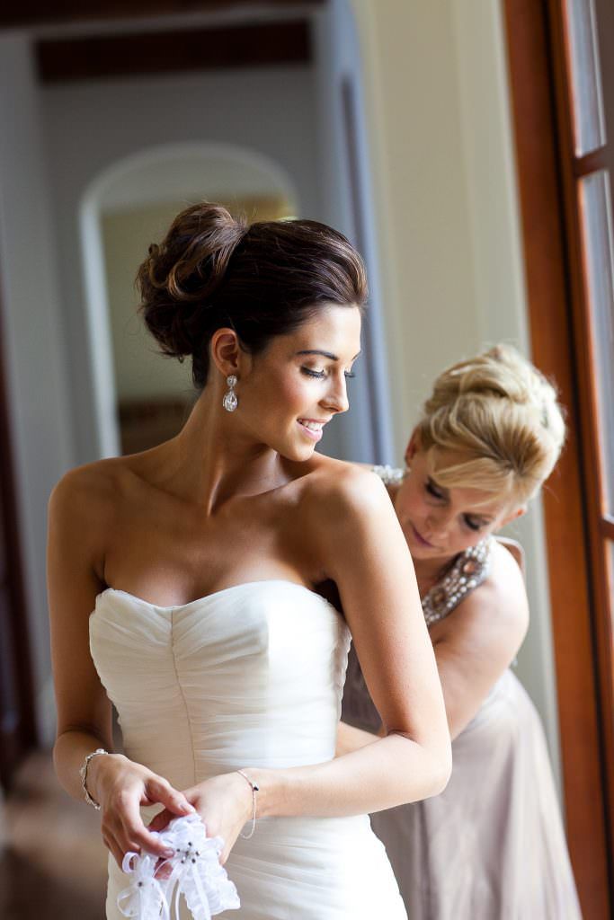 A woman is helping a bride get ready for her wedding.