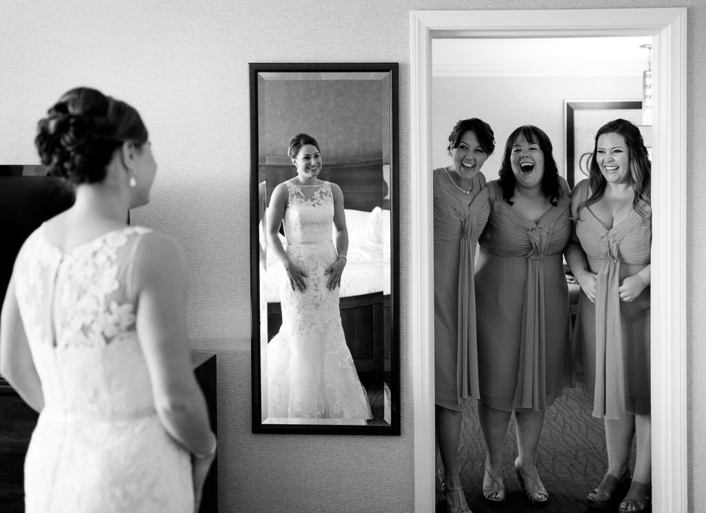 A bride and her bridesmaids are looking at their reflection in a mirror.