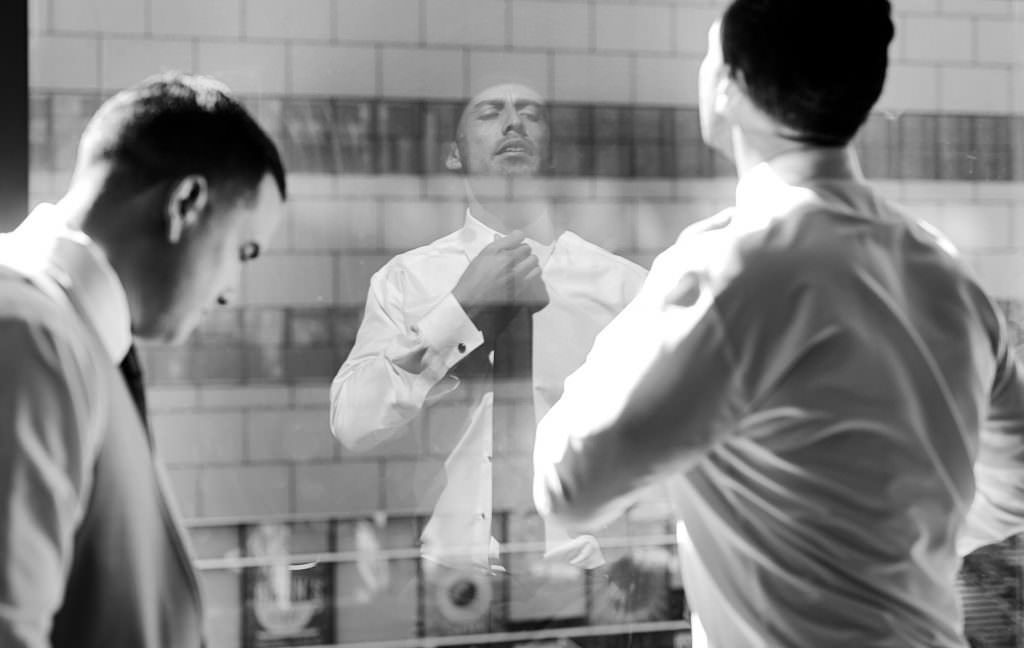 Two men are looking at their reflection in a mirror.