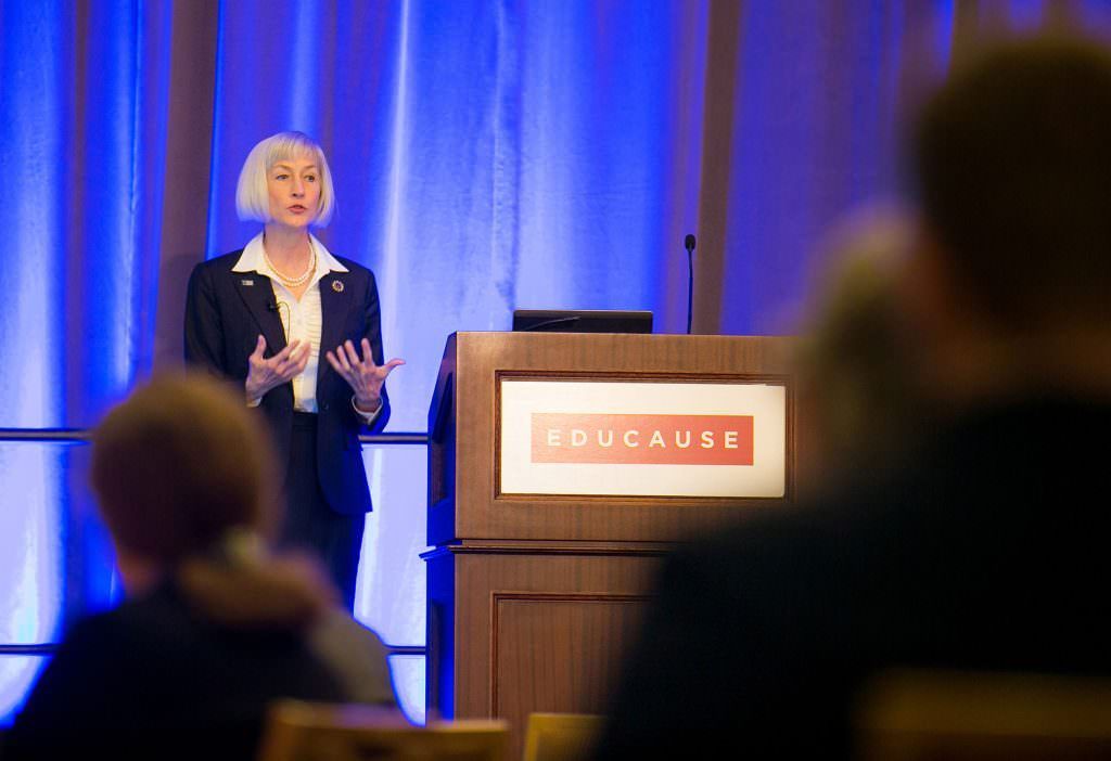 A woman is standing at a podium giving a presentation to a group of people.