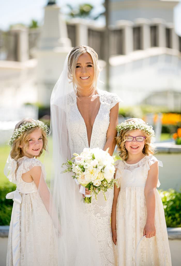 A bride and her two flower girls are posing for a picture.