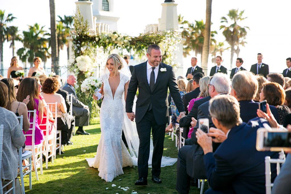 A bride and groom are walking down the aisle at their wedding at the Hyatt in Huntington Beach