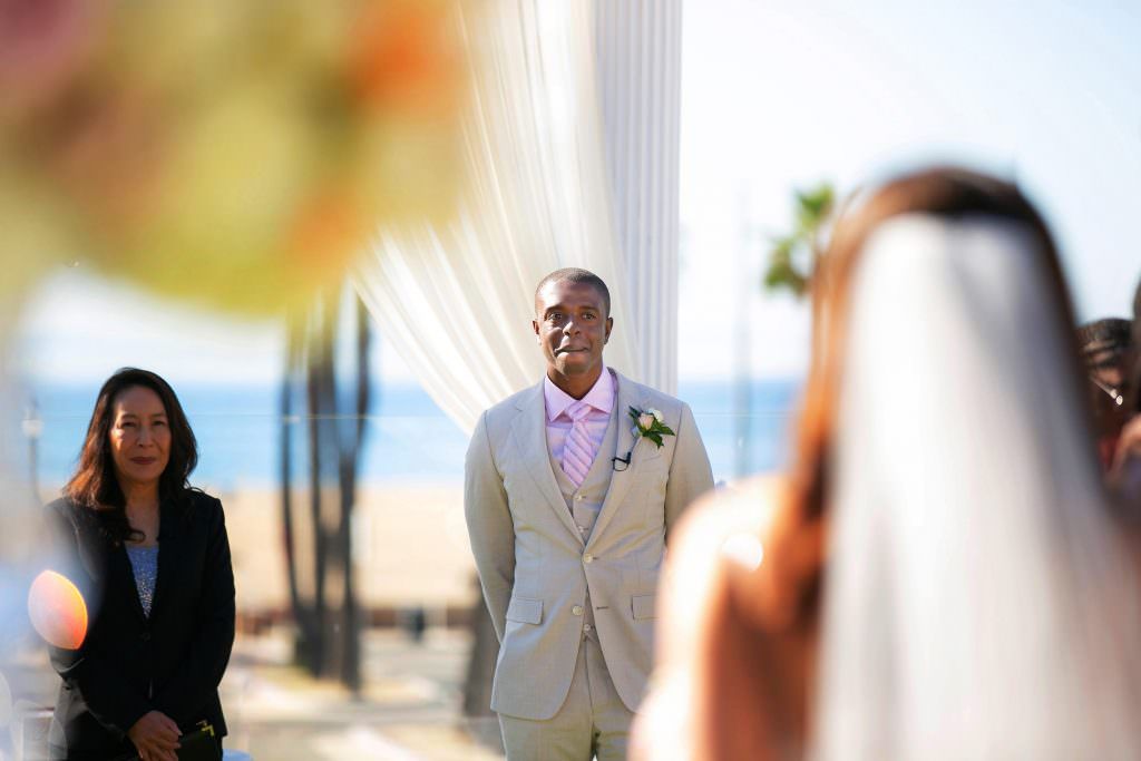 A bride and groom are walking down the aisle at a beach wedding.