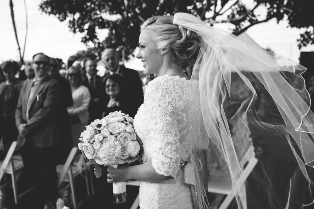 The bride is wearing a veil and holding a bouquet of flowers.