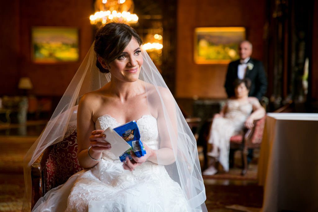 A bride in a wedding dress is sitting in a chair holding a card.