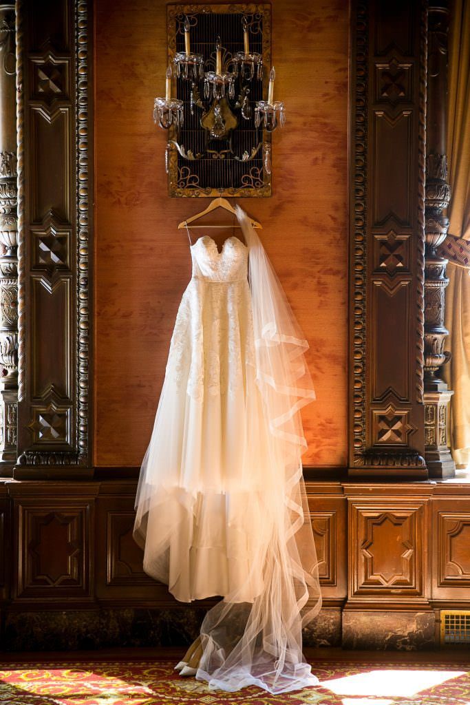 A wedding dress is hanging on a hanger in a room.