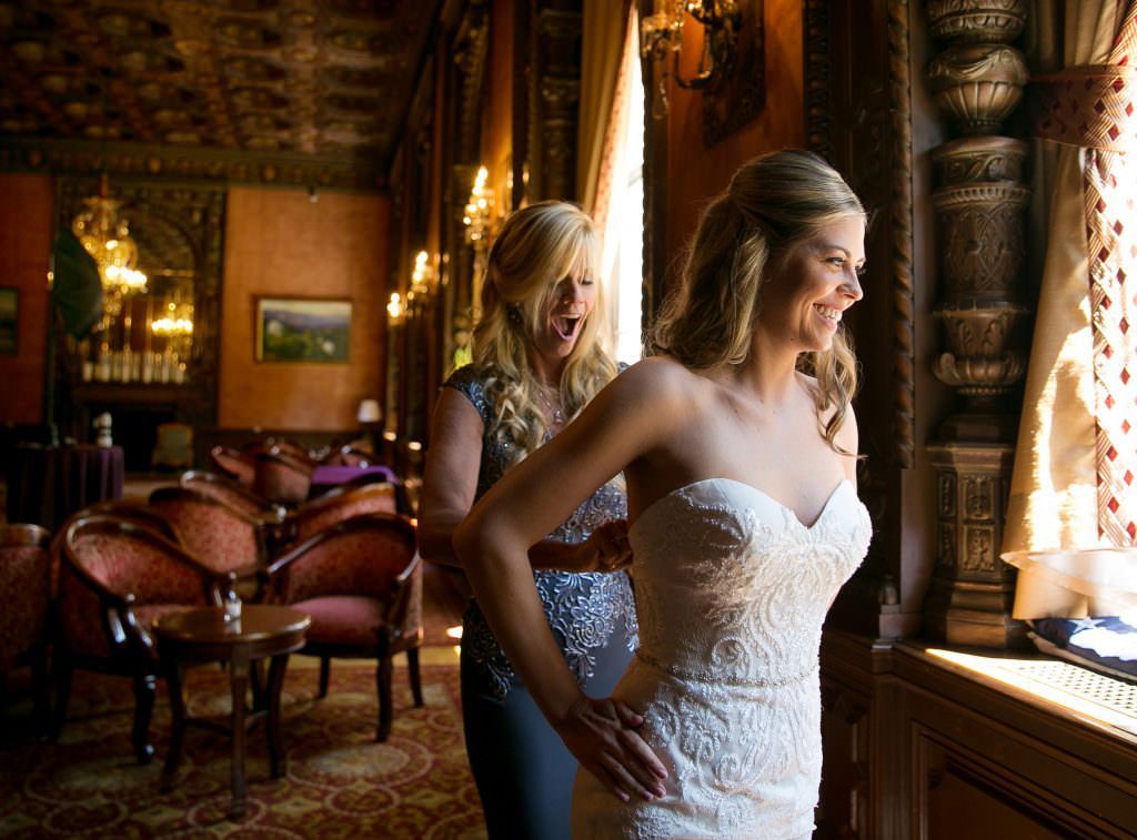 A woman is helping a bride get ready for her wedding.