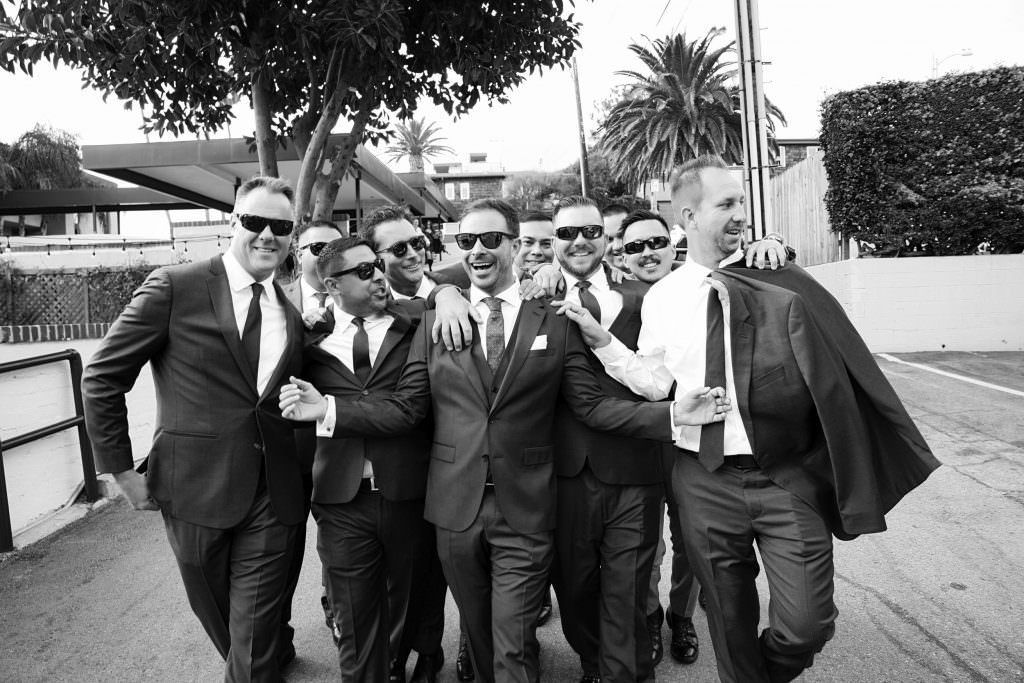 Groomsmen are walking to a lead ceremony with their group in Laguna Beach