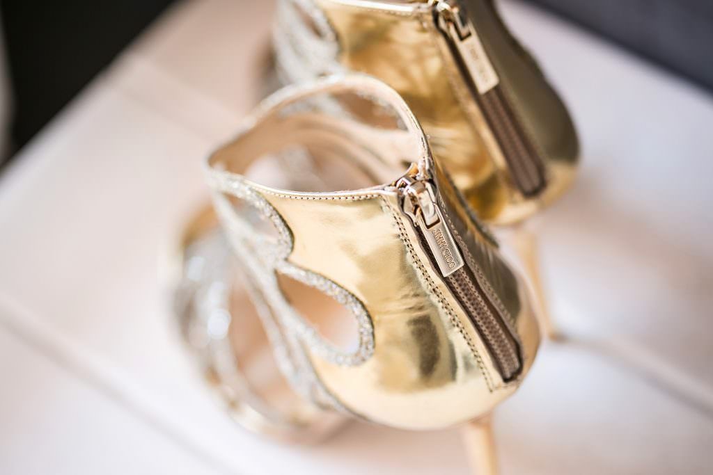 A pair of gold high heels sitting on top of a white table.