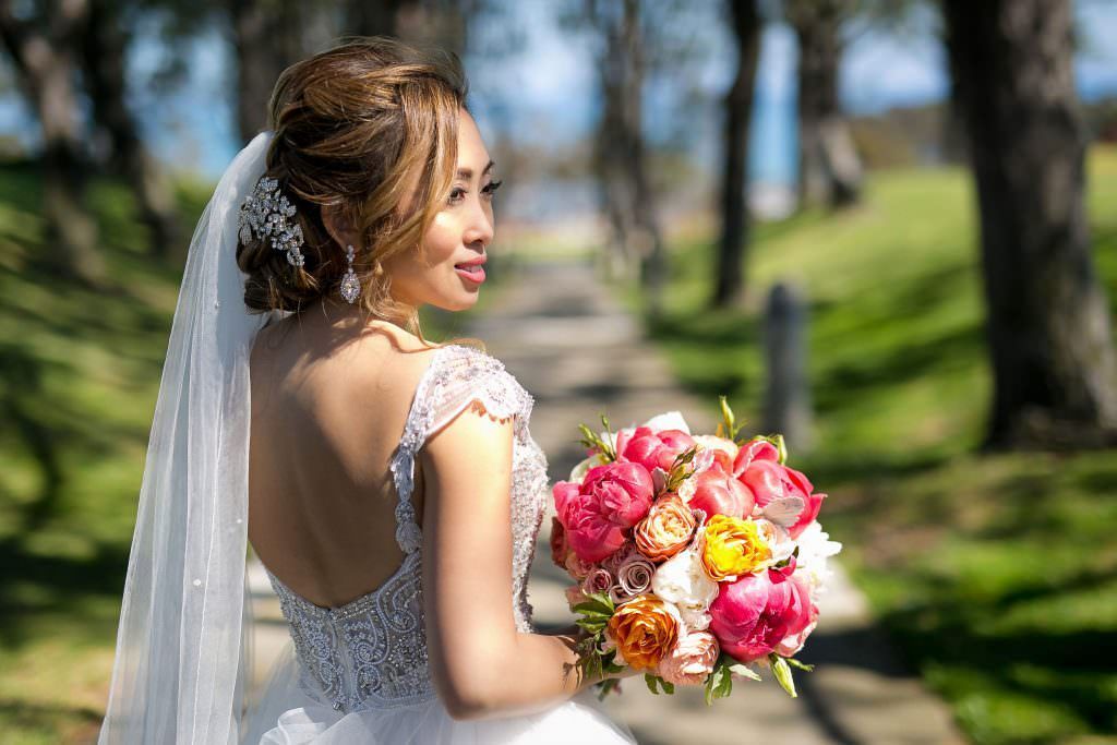 A bride in a wedding dress is holding a bouquet of flowers at the  Laguna Cliffs Marriott
