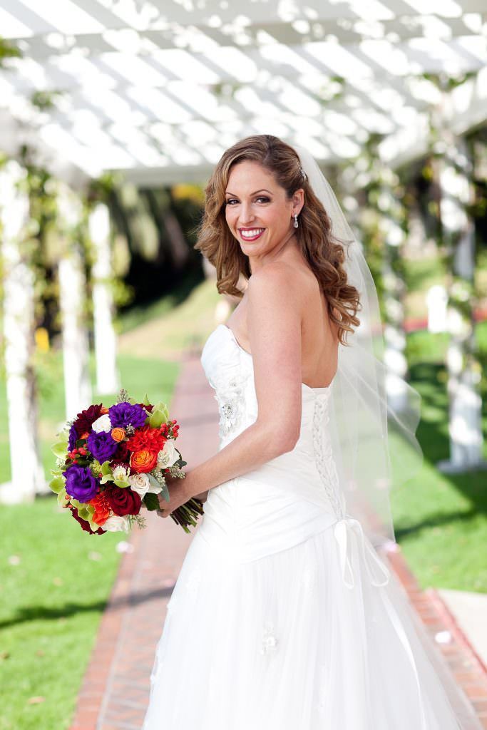 A bride in a wedding dress is holding a bouquet of flowers at the Hyatt in Newport Beach.