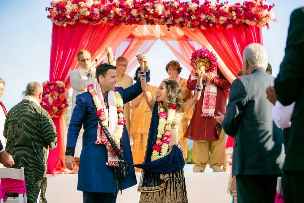 A bride and groom are giving each other a high five at their wedding ceremony at the Laguna Cliffs Marriott in Orange County.