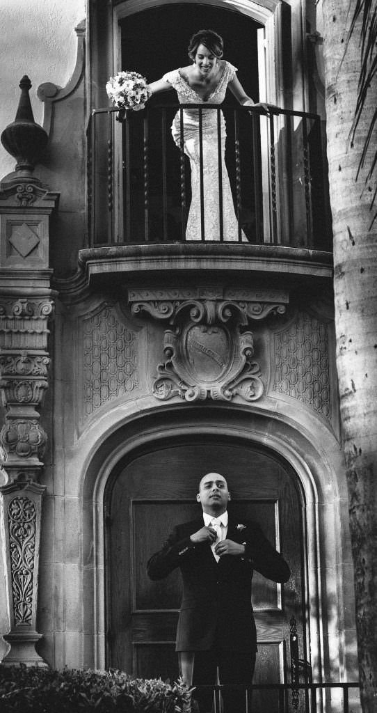 A black and white photo of a bride and groom on a balcony