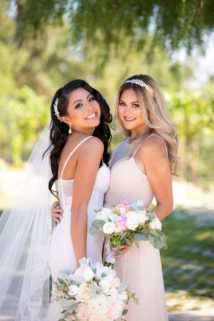 A bride and her bridesmaid are posing for a picture together.