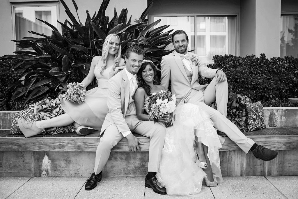 A bride and groom are posing for a black and white photo with their wedding party in Huntington Beach.