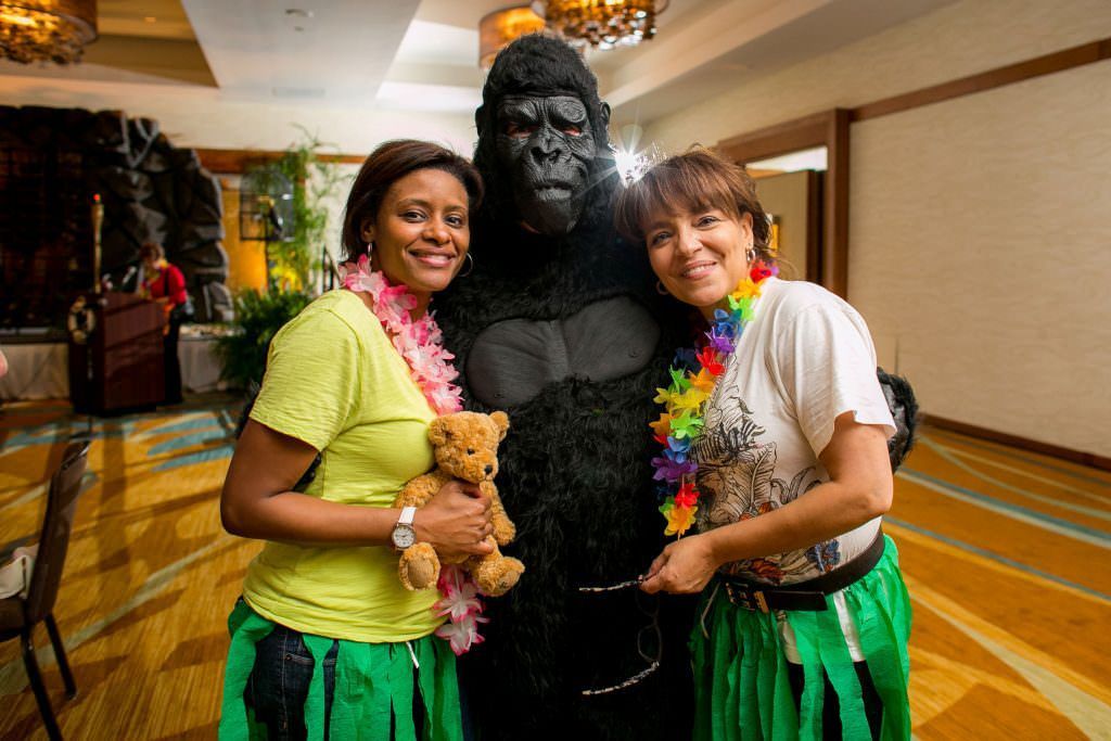 Two women are posing for a picture with a gorilla costume.