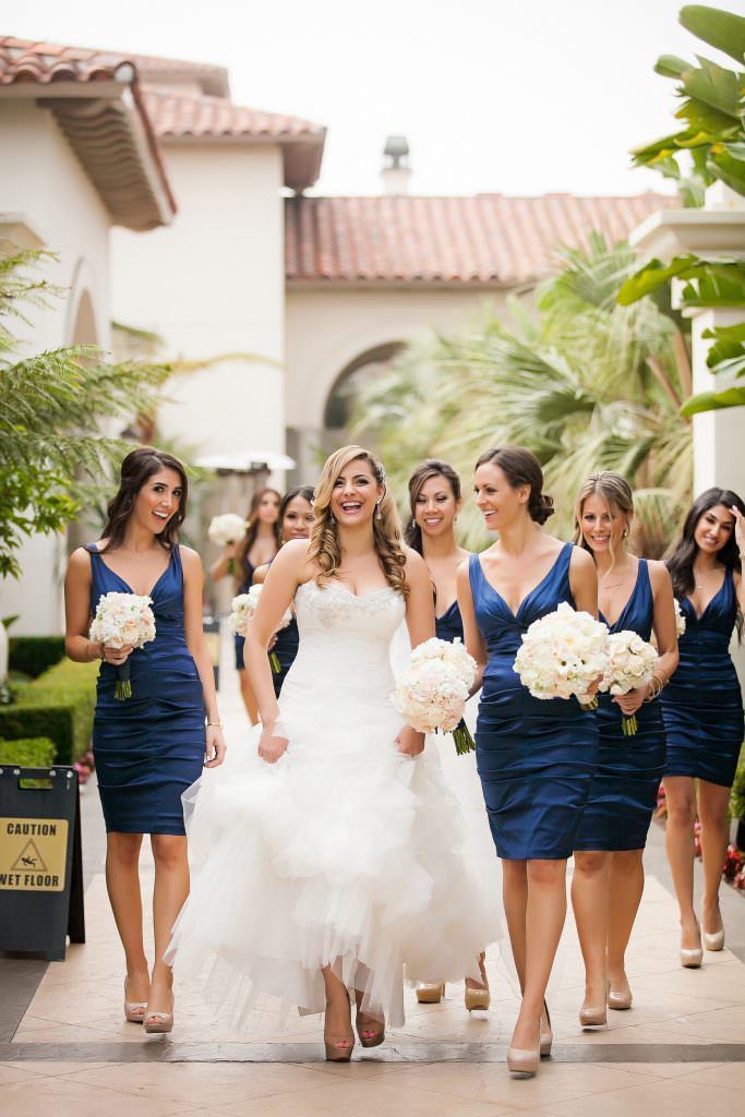 A bride and her bridesmaids are walking down a sidewalk at the Waldorf Astoria Hotel.
